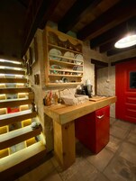 A kitchen with wooden shelves, a red cabinet, and a countertop with various kitchen items.