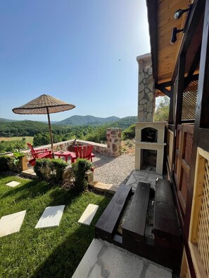 An outdoor patio with a stone fireplace, red chairs, and an umbrella. - Agva Heaven Hill (Sile)