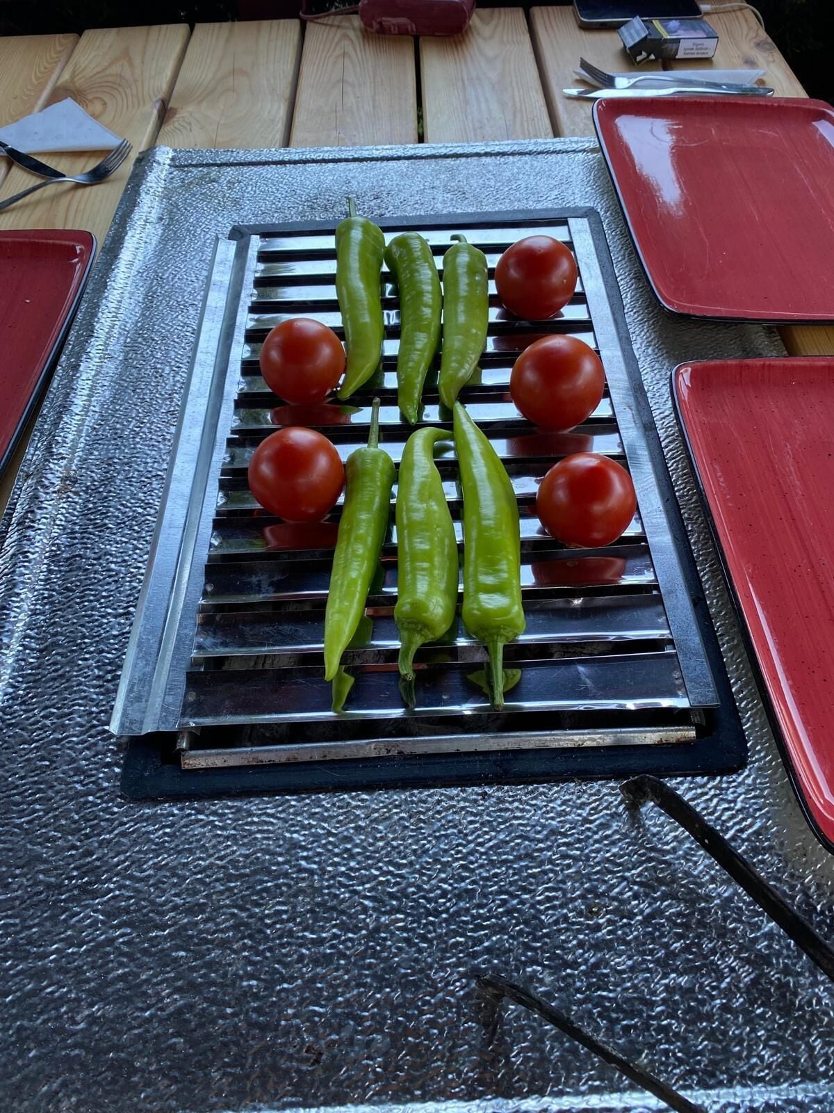 A grill with green peppers and tomatoes on a textured surface.