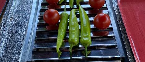 A grill with green peppers and tomatoes on a textured surface.