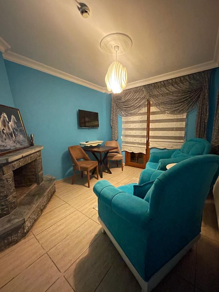 A living room with a fireplace, blue walls, a dining table with chairs, and a sofa.