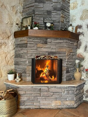 Una chimenea de piedra con repisa, un reloj y elementos decorativos.
