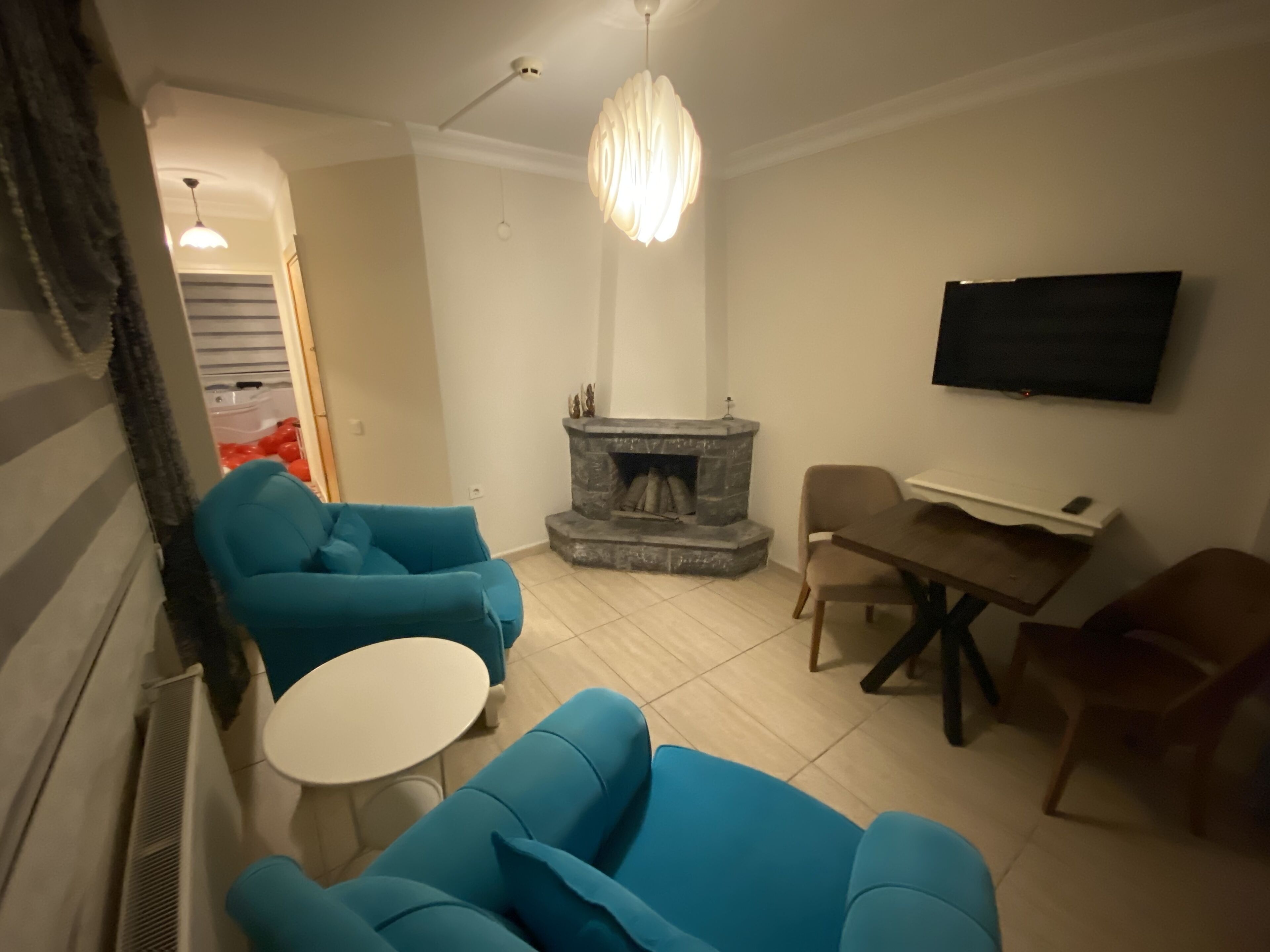 Ein Wohnzimmer mit Kamin, Fernseher und einer Sitzgruppe, darunter ein blaues Sofa und ein Tisch.