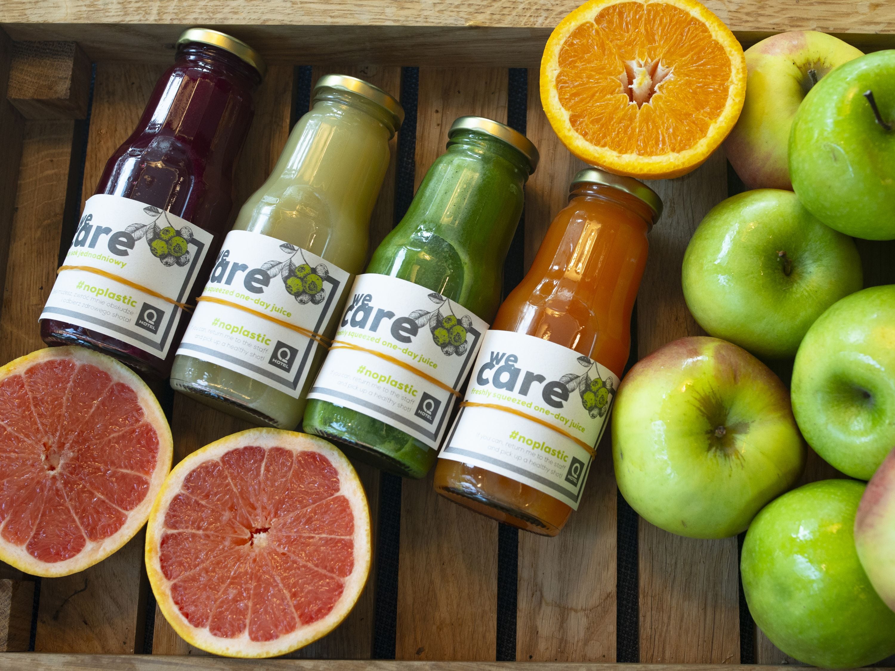 A wooden tray with various fruit and juice bottles.