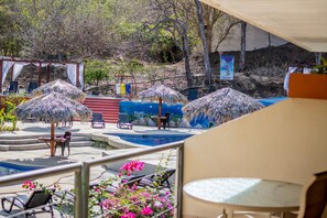 A pool area with thatched umbrellas, lounge chairs, and a small pool. - Villas Playa Hermosa Beach Hotel (Sardinal)