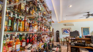 Eine Bar mit Regalen voller Spirituosenflaschen, einem Computer und einem Deckenventilator.