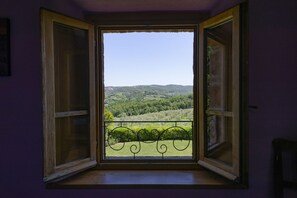 An open window with a view of a green landscape and hills. - Locanda Vesuna (Trequanda)