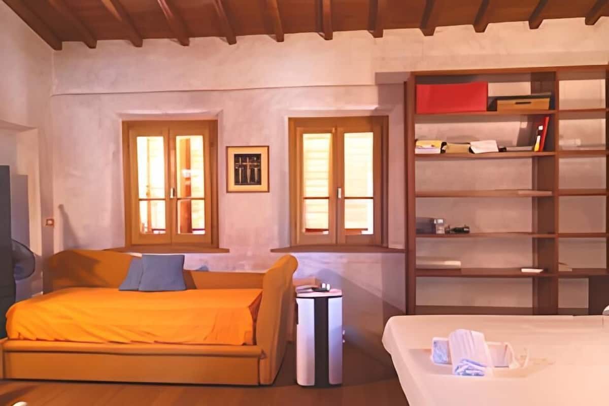 A bedroom with two beds, a bookshelf, and a small table.
