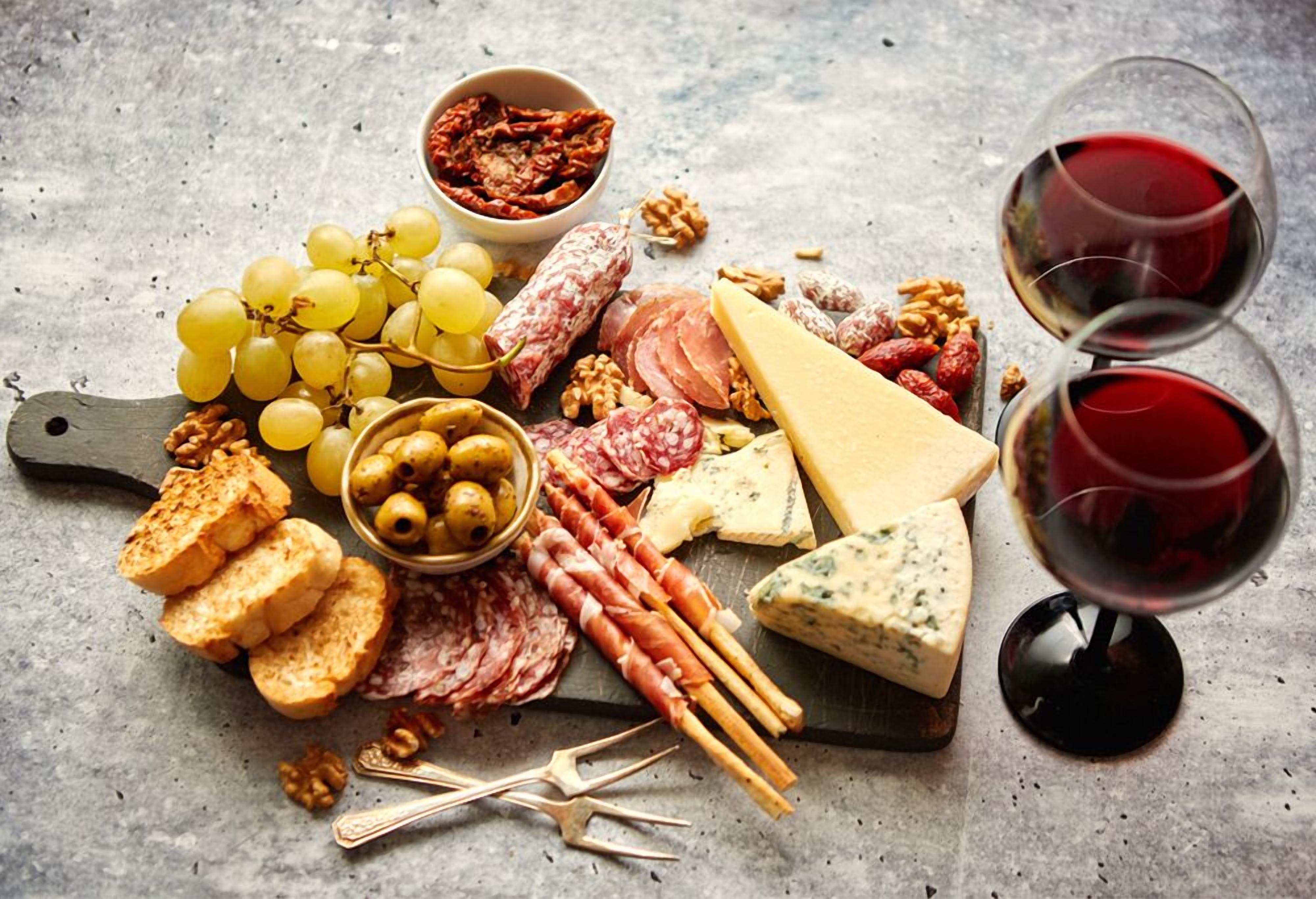 A charcuterie board with various cheeses, meats, nuts, grapes, and crackers.