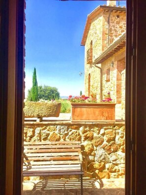 A stone building with a wooden bench and flower boxes. - Locanda Vesuna (Trequanda)