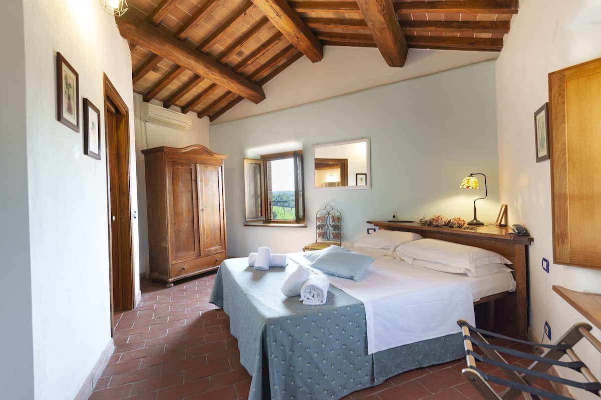 A bedroom with a bed, wooden wardrobe, and a window with a view.