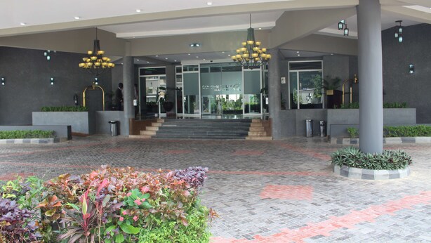A modern hotel entrance with a tiled floor, two chandeliers, and a glass door leading to the lobby. - Golden Tulip Ibadan (Ibadan)