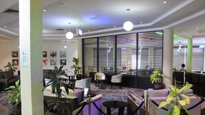 A lobby with seating areas, potted plants, and a reception desk. - Golden Tulip Ibadan (Ibadan)
