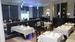 A restaurant with multiple tables set for dining, a bar area, and a counter. - Golden Tulip Ibadan (Ibadan)