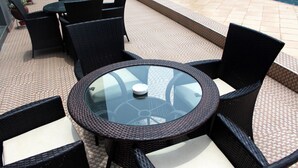 A round glass table with black wicker chairs, surrounded by a patterned floor. - Golden Tulip Ibadan (Ibadan)