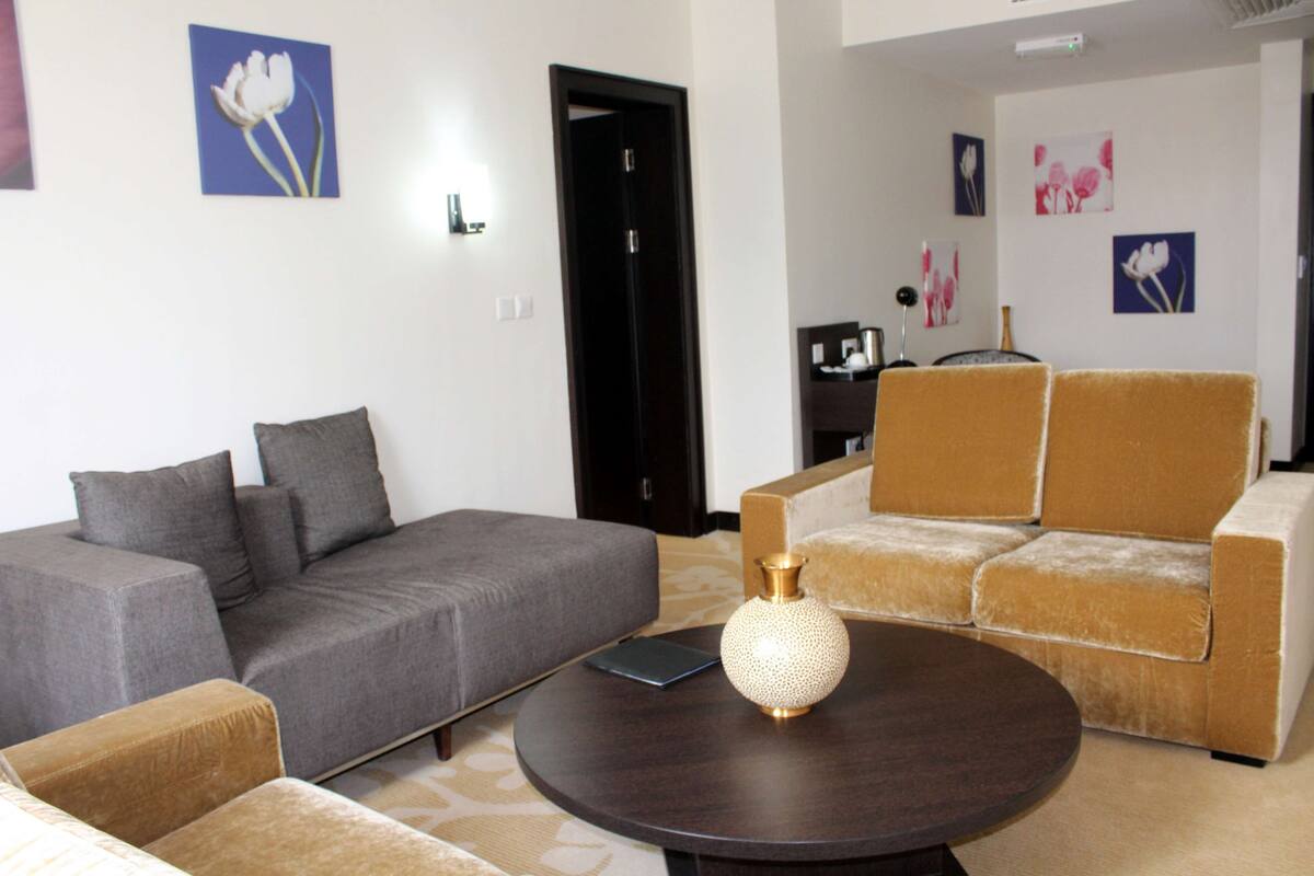 A modern living room with a grey sofa, a brown armchair, and a round coffee table with a vase.