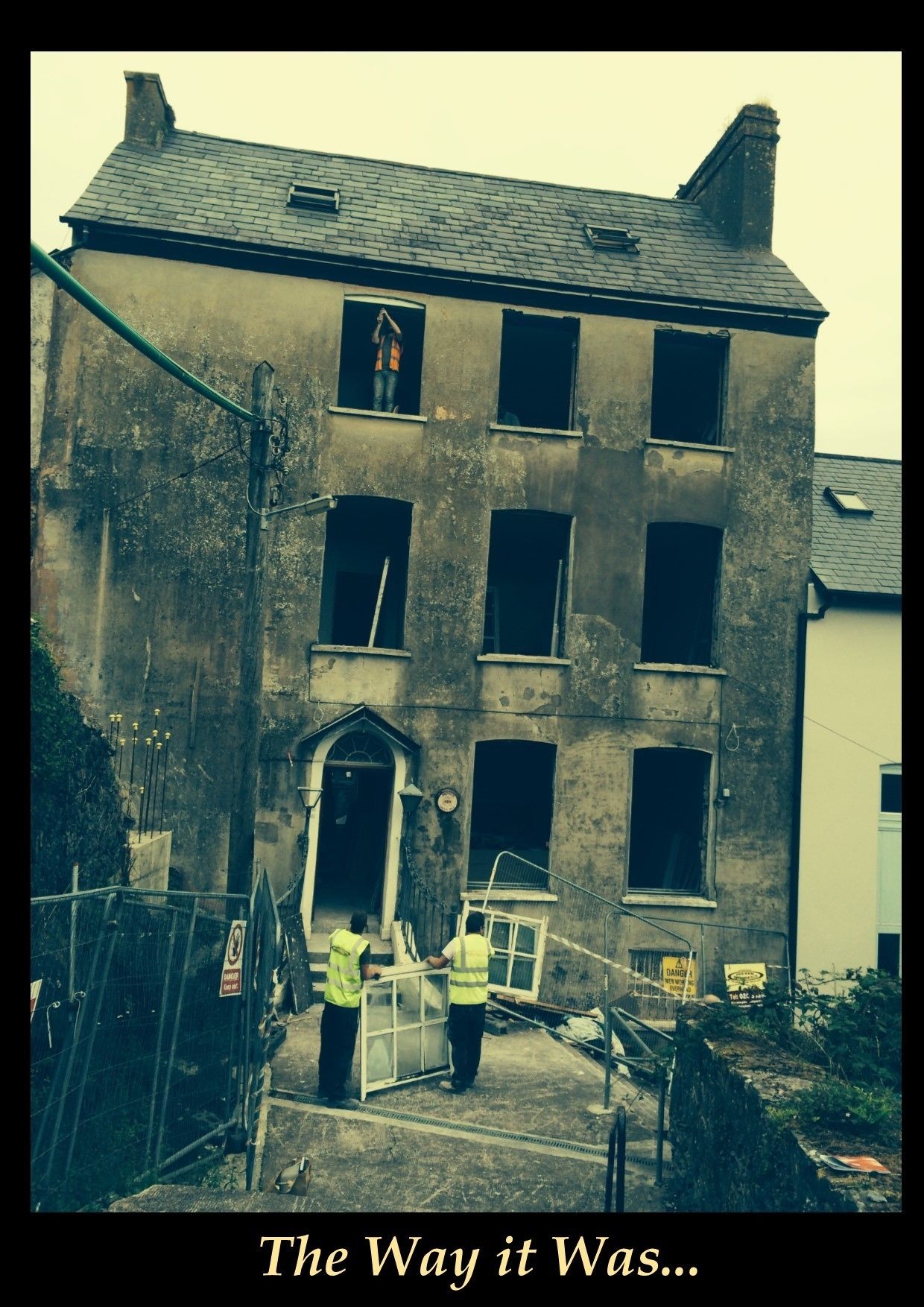 Un bâtiment délabré, aux fenêtres murées, et une personne debout sur le toit.