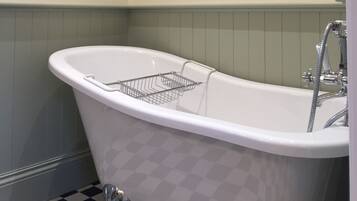 A white freestanding bathtub with a chrome faucet and a chrome showerhead, a chrome shower hose, and a chrome shower head.