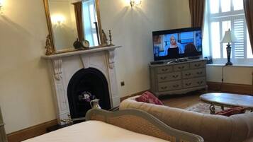 A bedroom with a large bed, a television, a fireplace, and a chandelier.