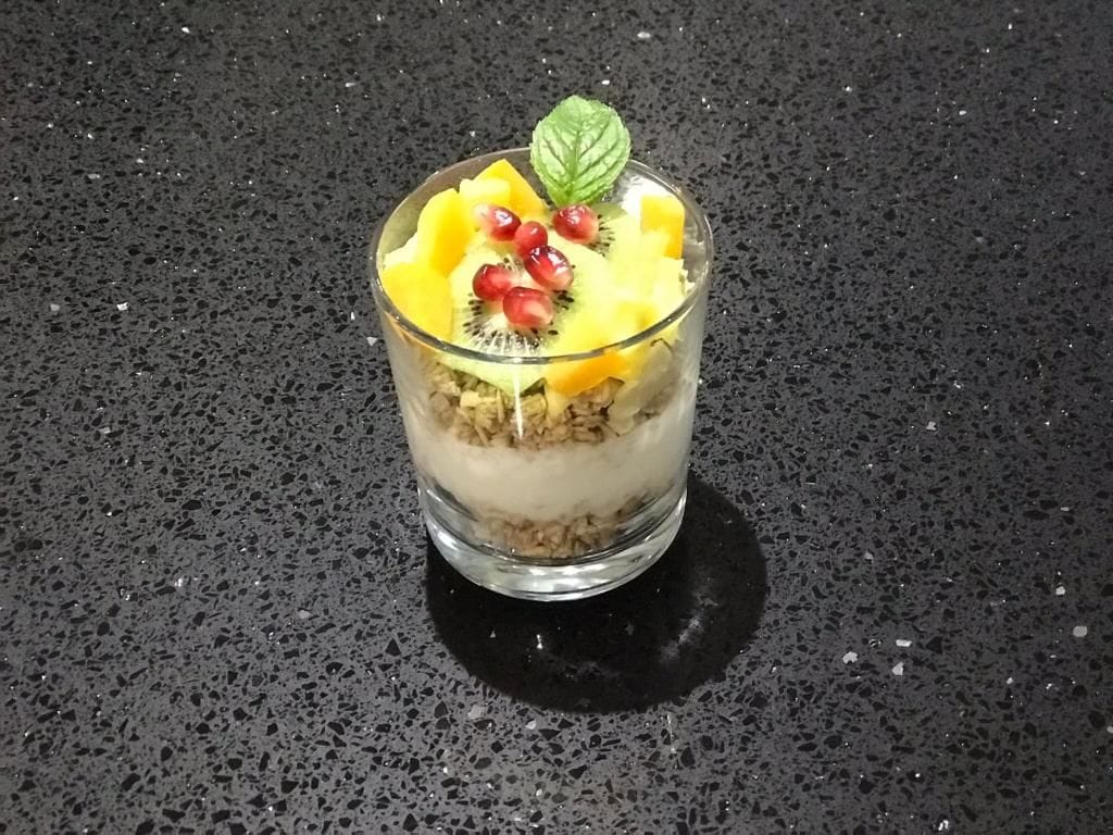 A dessert in a clear glass on a textured surface.