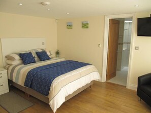 A bedroom with a bed, bedside table, and a door leading to a bathroom. - Tidmoor Farm Vegetarian B&B (Weymouth)