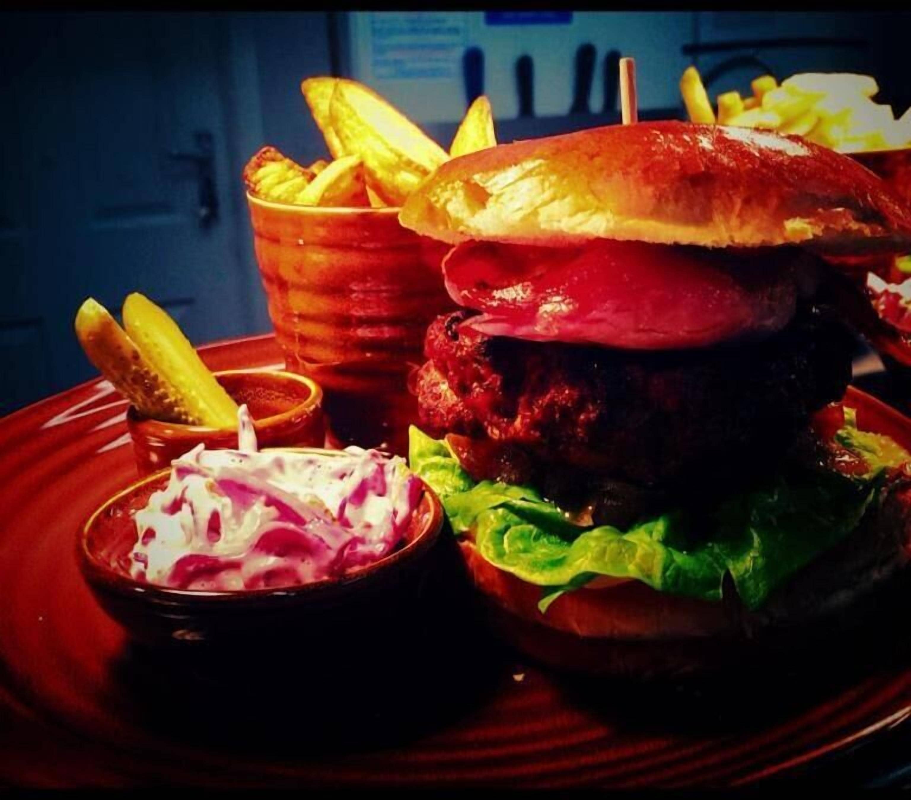 En hamburgare med pommes frites och coleslaw på en tallrik.