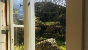 A door leading to a garden with a large rock and grass.