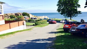 A coastal road with parked cars and a building on the left.
