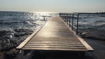 A wooden pier extending into the ocean with a metal railing on one side.