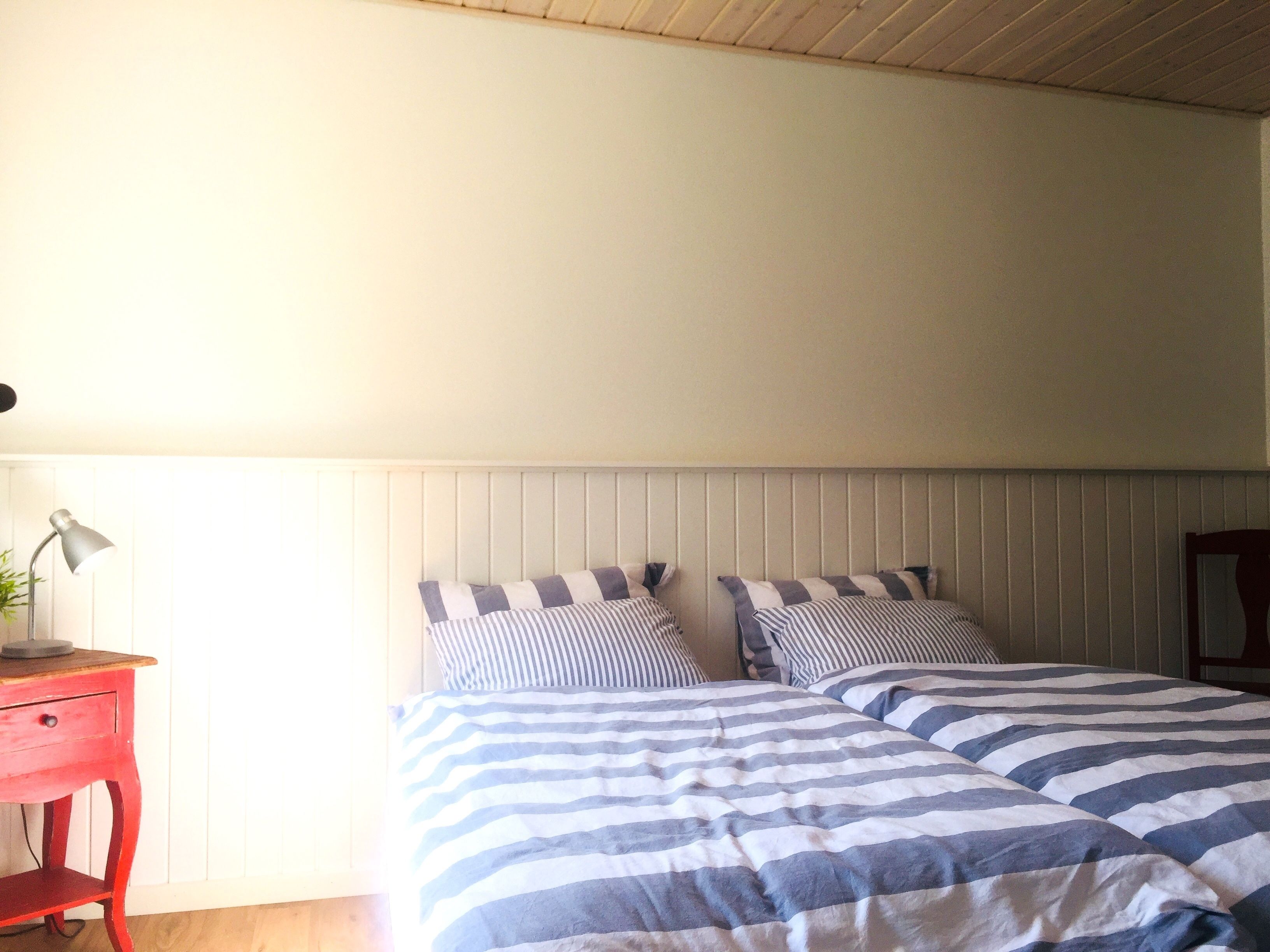 Ein Schlafzimmer mit zwei Betten, einem roten Nachttisch und einer Lampe.