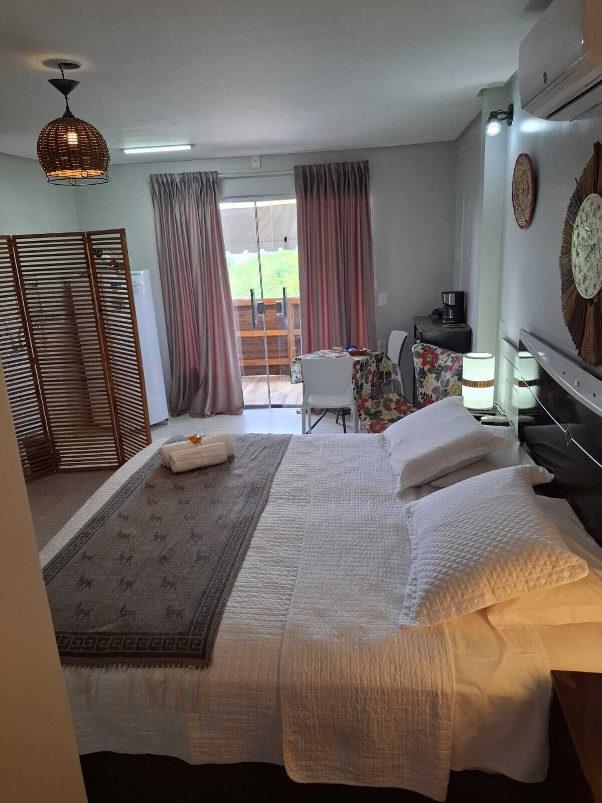 Une chambre d’hôtel avec un grand lit, un bureau, une chaise et une vue sur l’extérieur.