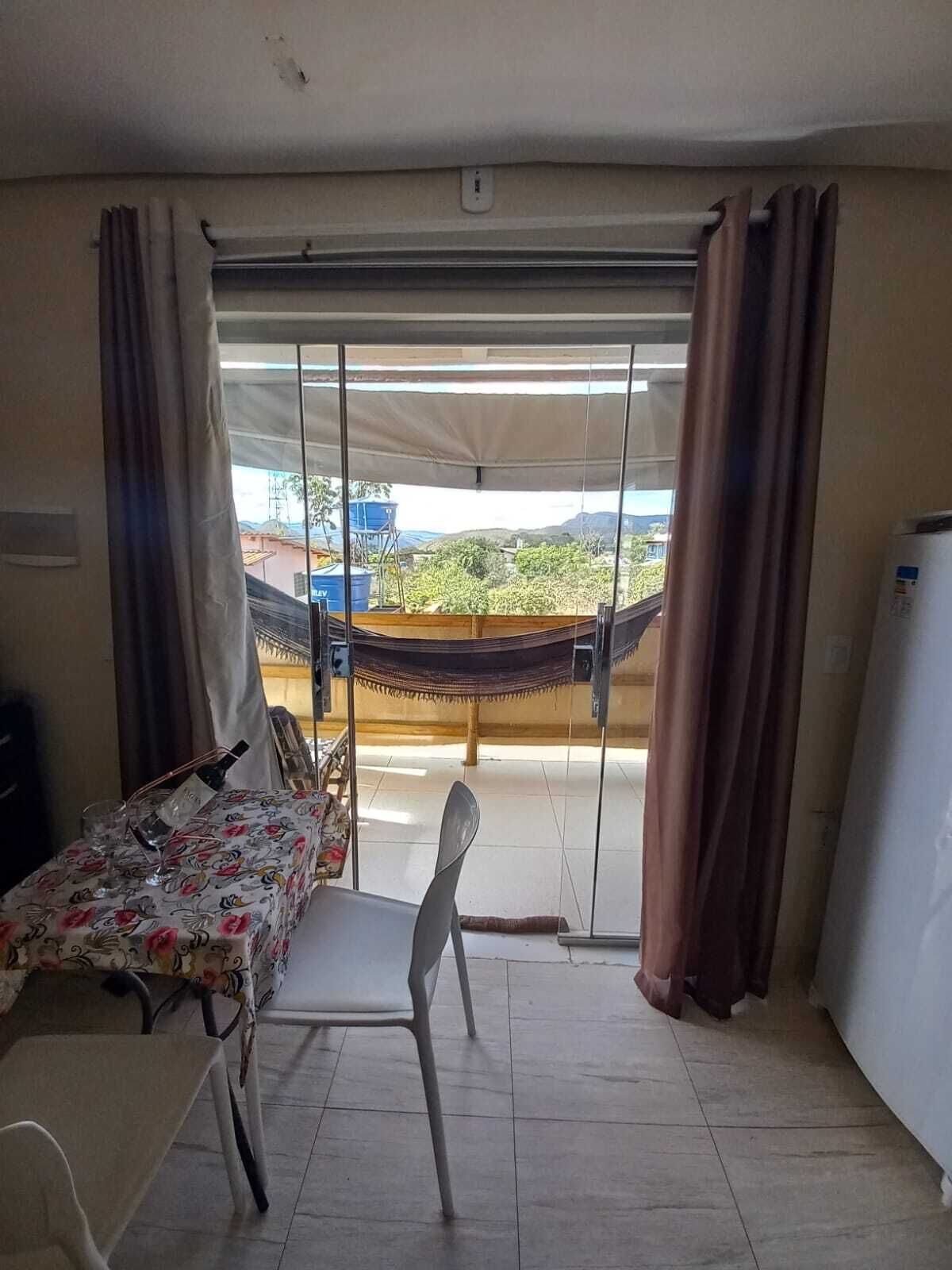 A room with a dining table, chairs, a hammock, and a view of greenery outside.