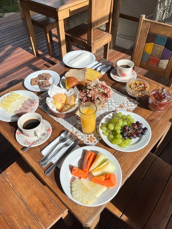 Una mesa de madera dispuesta con diversos productos para el desayuno, como pan, pasteles, frutas y bebidas.