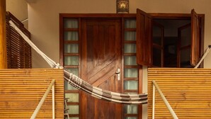 Una escalera de madera con una hamaca, una puerta de madera y una planta en maceta.