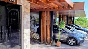 Un edificio con recepción, aparcamiento y una fila de coches estacionados.