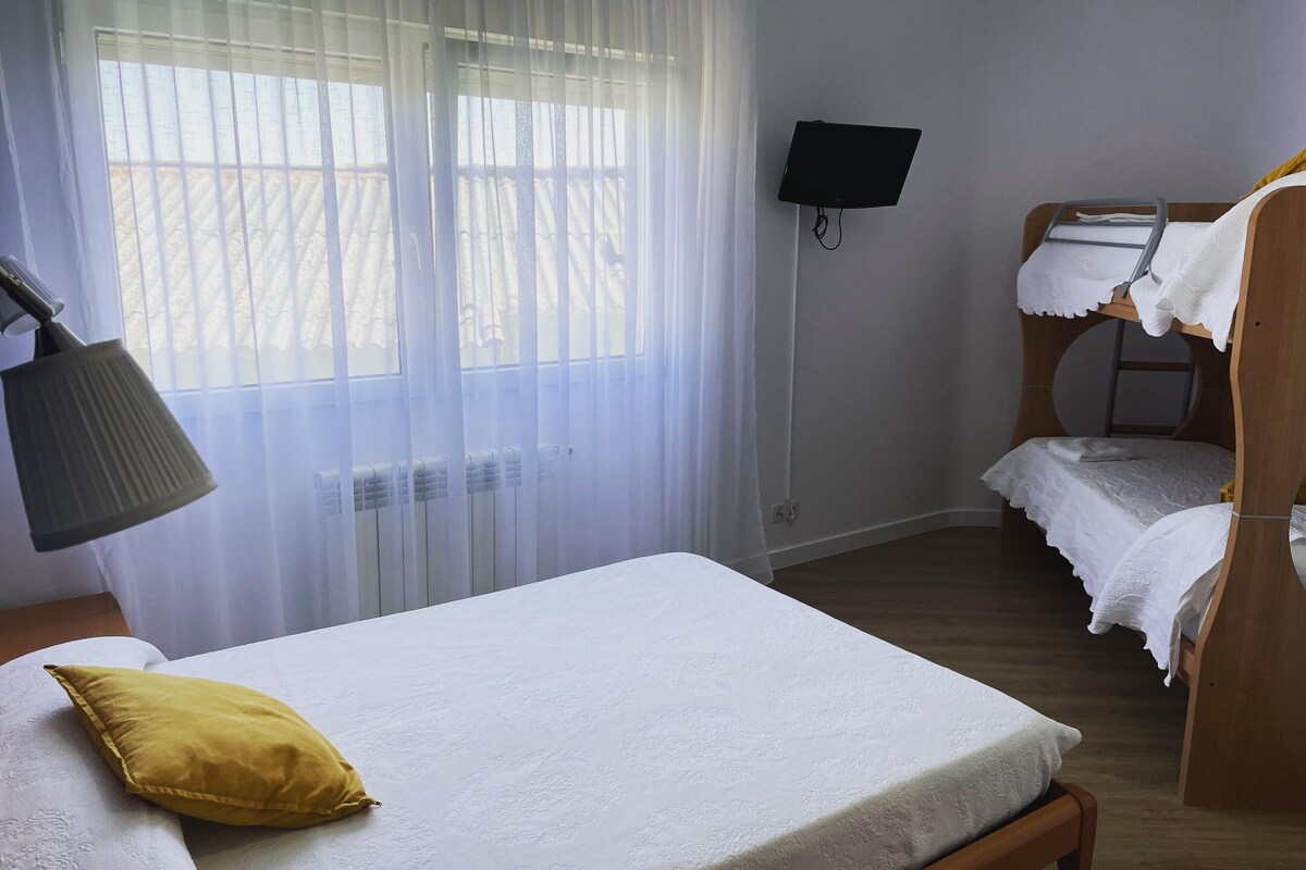 Ein Schlafzimmer mit einem Einzelbett, einem Nachttisch mit Lampe, einem an der Wand befestigten Fernseher und einem Stockbett.