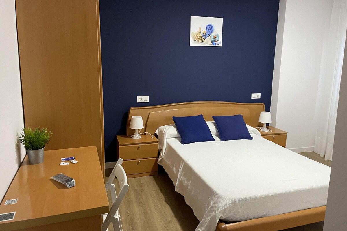 Ein Hotelzimmer mit Bett, Nachttischen, einem Schreibtisch und einem Stuhl.