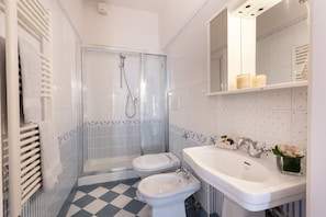 A bathroom with a shower, toilet, bidet, and sink. - Alfani Terrace (Florence)