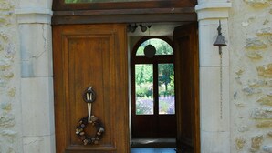 Uma porta arqueada com uma porta de madeira, uma grinalda e um sino na parede.