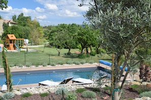 A backyard with a swimming pool, lounge chairs, and a children's play area. - La Monèze Basse (Malras)