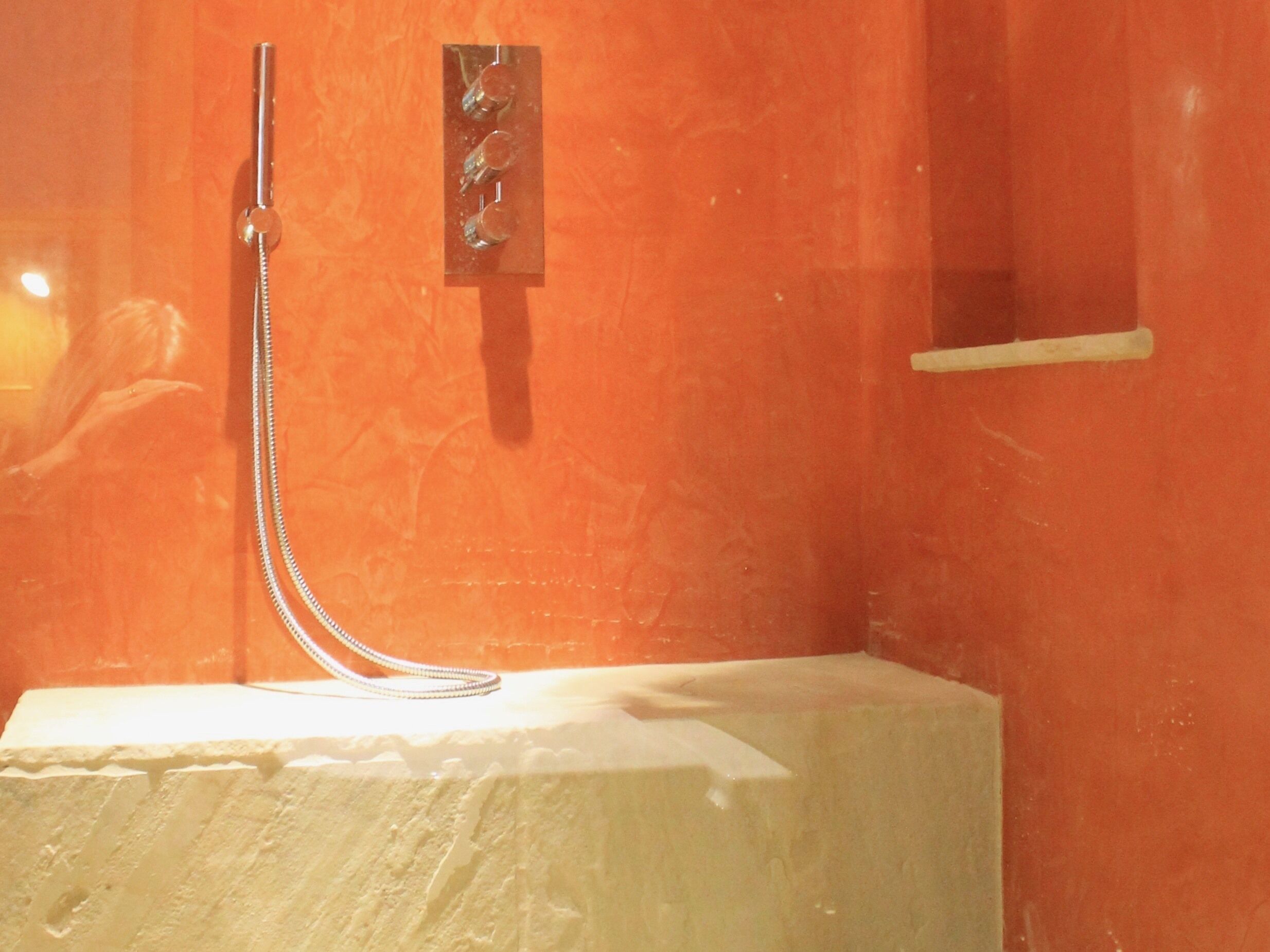 A bathroom with a shower, a mirror, and a white pedestal.