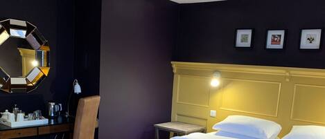 A hotel room with a bed, two chairs, a desk, a mirror, and a nightstand.