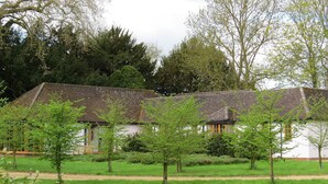 A traditional building with a tiled roof, surrounded by a well-maintained lawn and trees. - The Lodge at Hemingford Grey House (Huntingdon)