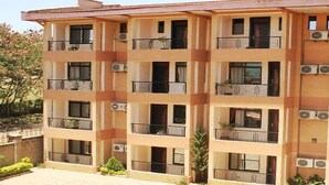 A multi-story building with balconies, air conditioning units, and a paved courtyard. - Le Savanna Country Lodge And Hotel (Kisumu)