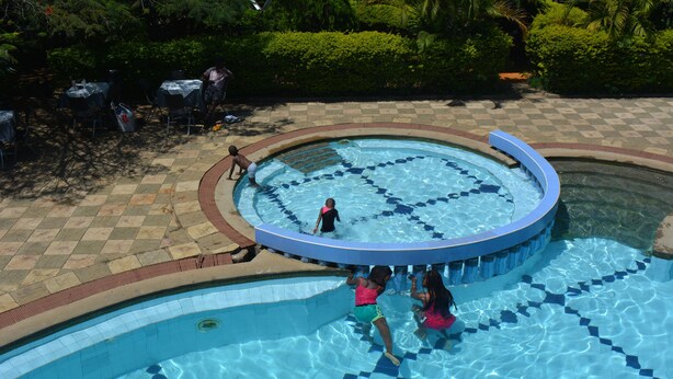 A swimming pool with a checkered pattern around the edge, surrounded by a paved area with tables and chairs. - Le Savanna Country Lodge And Hotel (Kisumu)