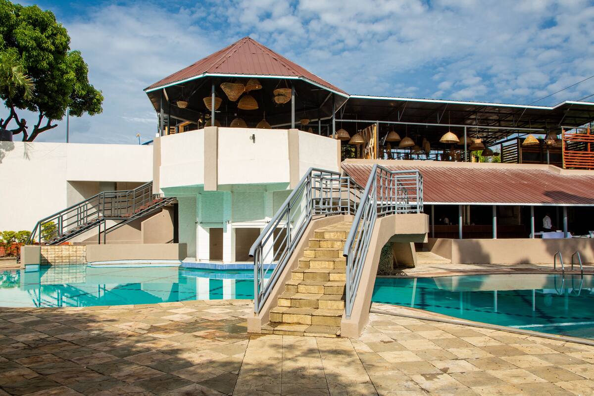 A pool area with a covered seating area and stairs leading to a roofed section.