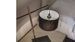 A bed with a black headboard, a bedside table, and a lamp. - Alfani Views (Florence)