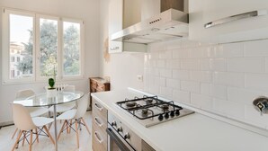 A modern kitchen with a gas stove, white cabinets, and a glass dining table. - Alfani Views (Florence)