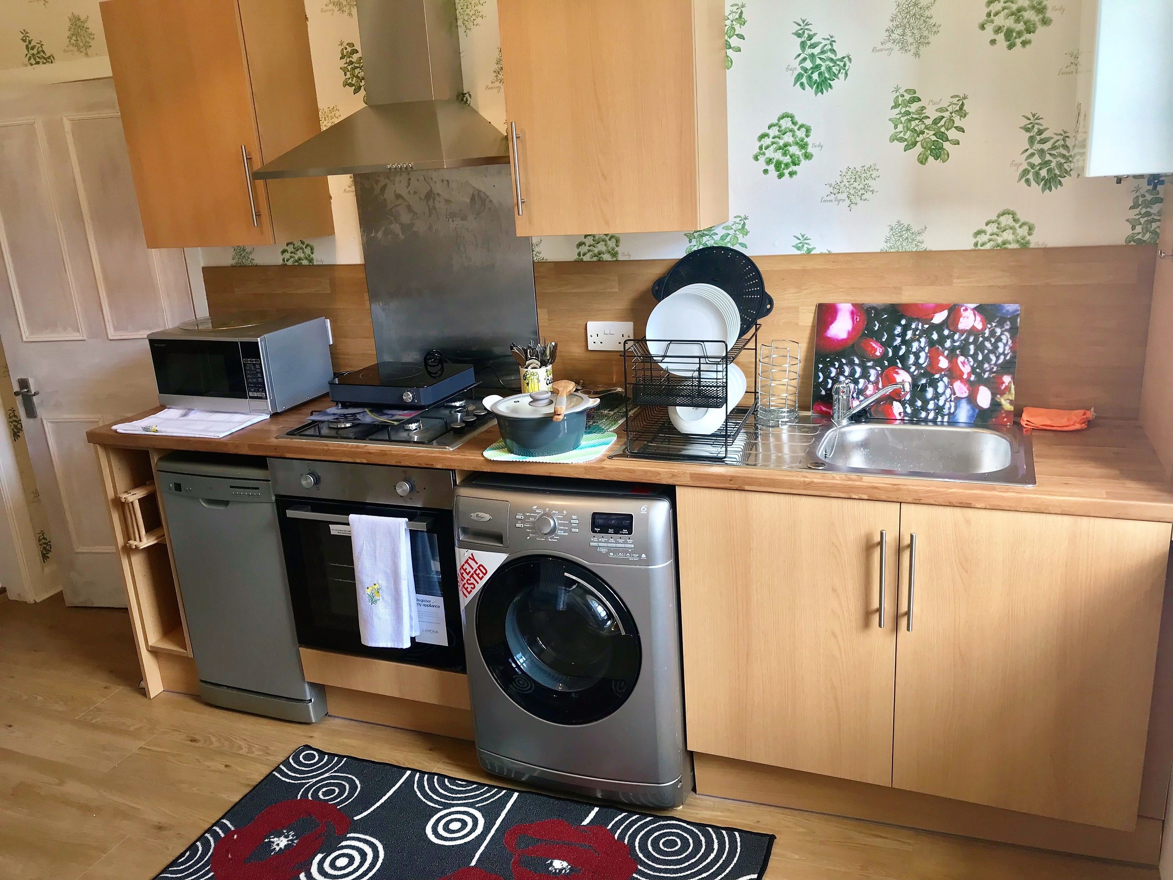 A compact kitchen with a microwave, stove, sink, and dishwasher.