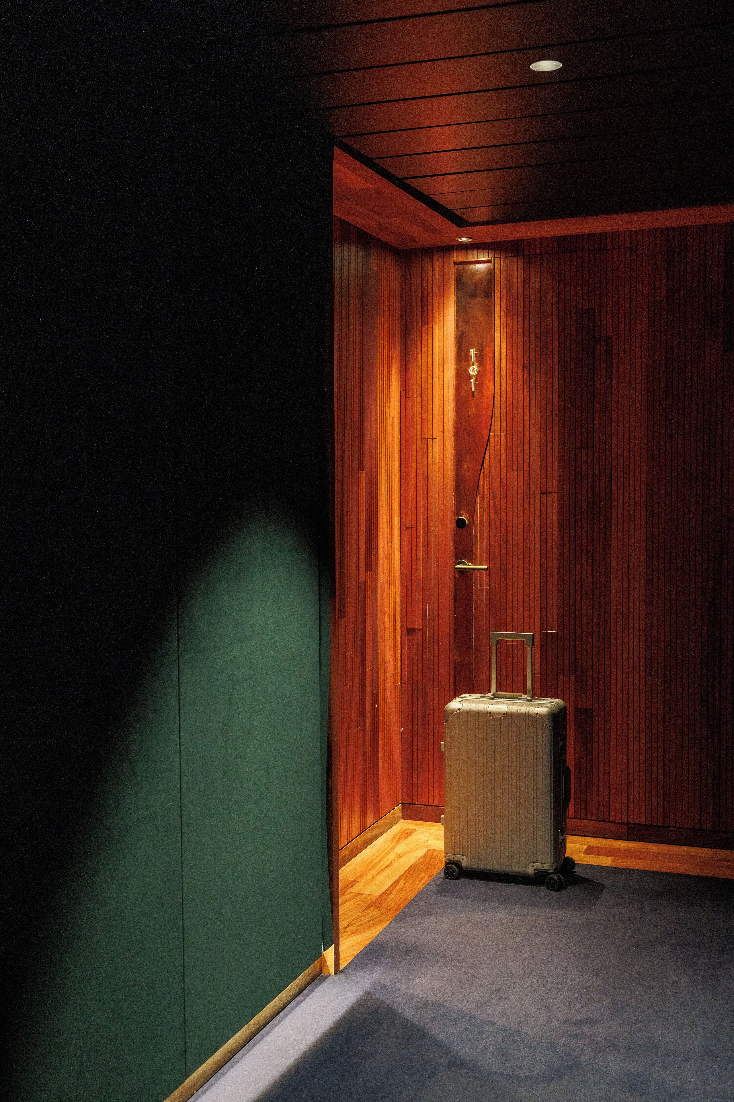 A room with wooden paneling, a suitcase, and a door with a handle.